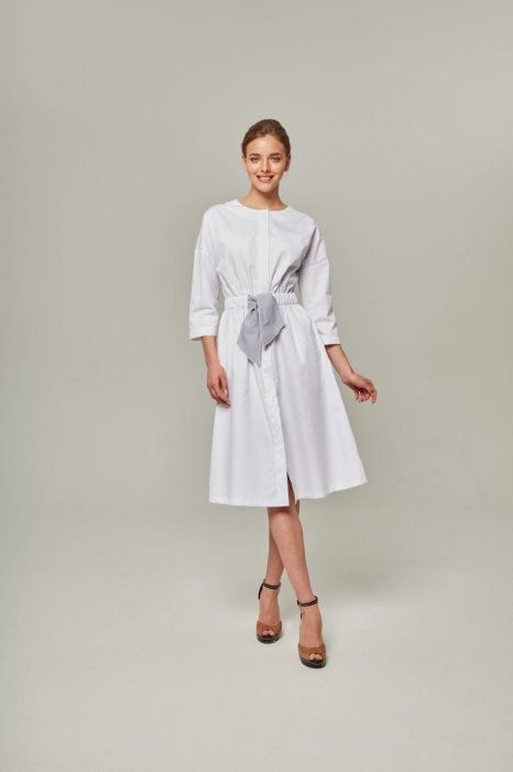 Халат медицинский женский FDW008 Платье с приспущенным рукавом ¾, платье длины миди, с карманами в боковых швах. Приталено поясом-резинкой, впереди декорировано бантом. Застёжка супатного типа выполнена на кнопках.
